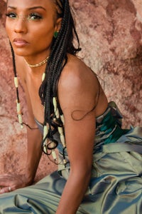 a black woman in a dress posing in front of rocks