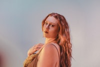 a woman with long red hair posing in front of a blue background