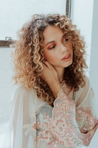 a woman with curly hair posing in front of a window