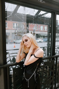 a woman in a black dress leaning on a balcony