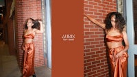 a woman in an orange dress leaning against a brick wall