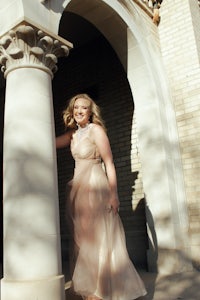 a woman in a long dress standing in front of a building