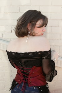 a woman in a corset leaning against a brick wall