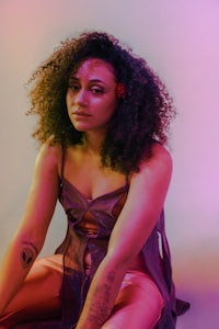 a woman with curly hair sitting on the floor