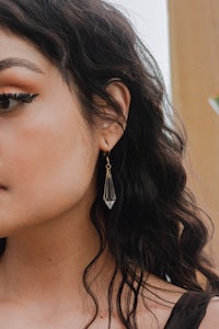 a woman wearing a black top and black earrings