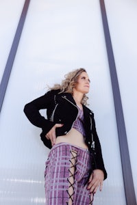 a woman in plaid pants posing in front of a wall