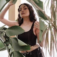 a woman posing in front of a plant