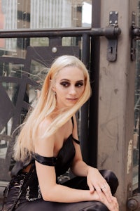 a woman in a black dress sitting on a railing