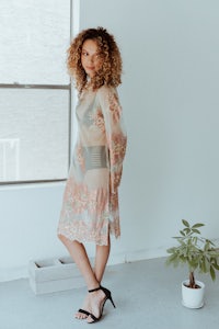 a woman in a floral dress standing in front of a window