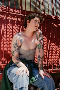 a woman with tattoos sitting on a fence