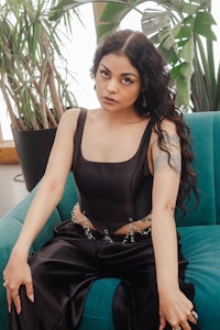 a woman in a black top and pants sitting on a blue couch