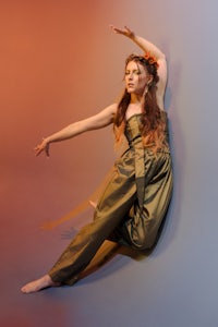 a woman in a green jumpsuit posing with her arms outstretched