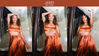 a woman in an orange dress posing in front of a window